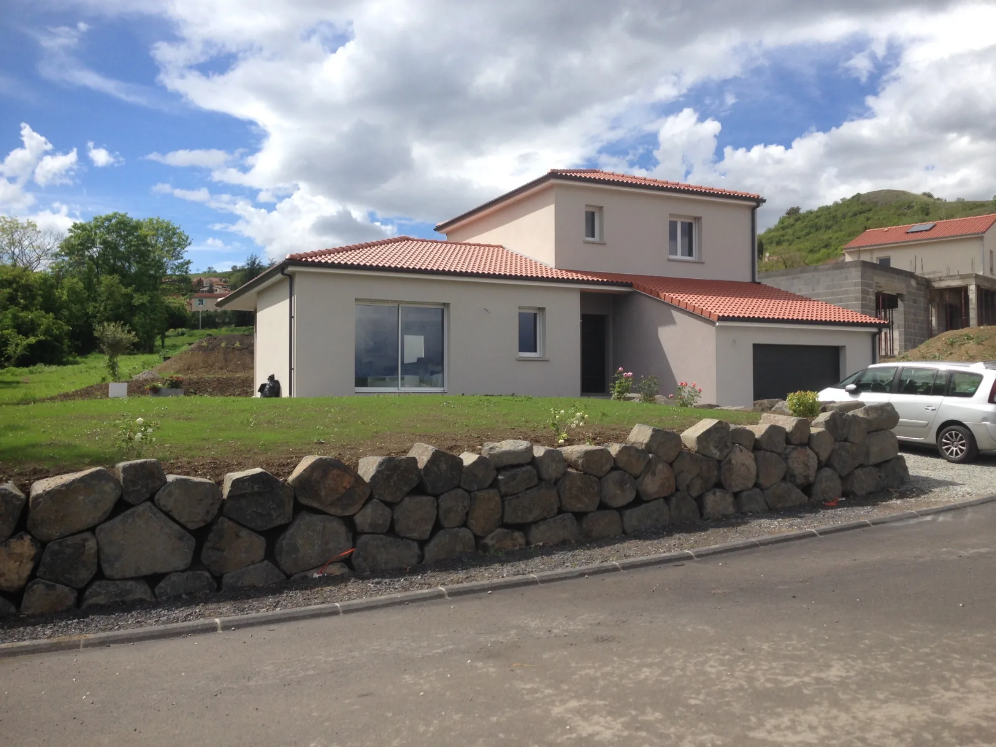 Maison neuve à étage au-dessus d'un mur en pierres de basalte