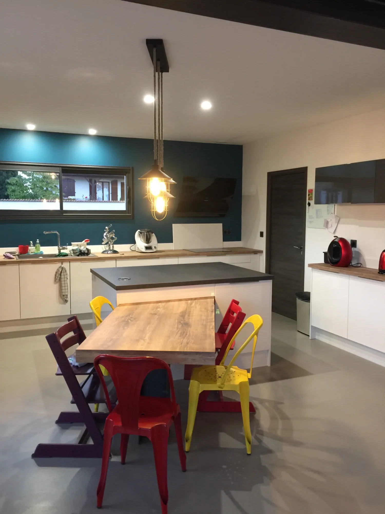 Cuisine ouverte avec îlot, table en bois et chaises de couleur
