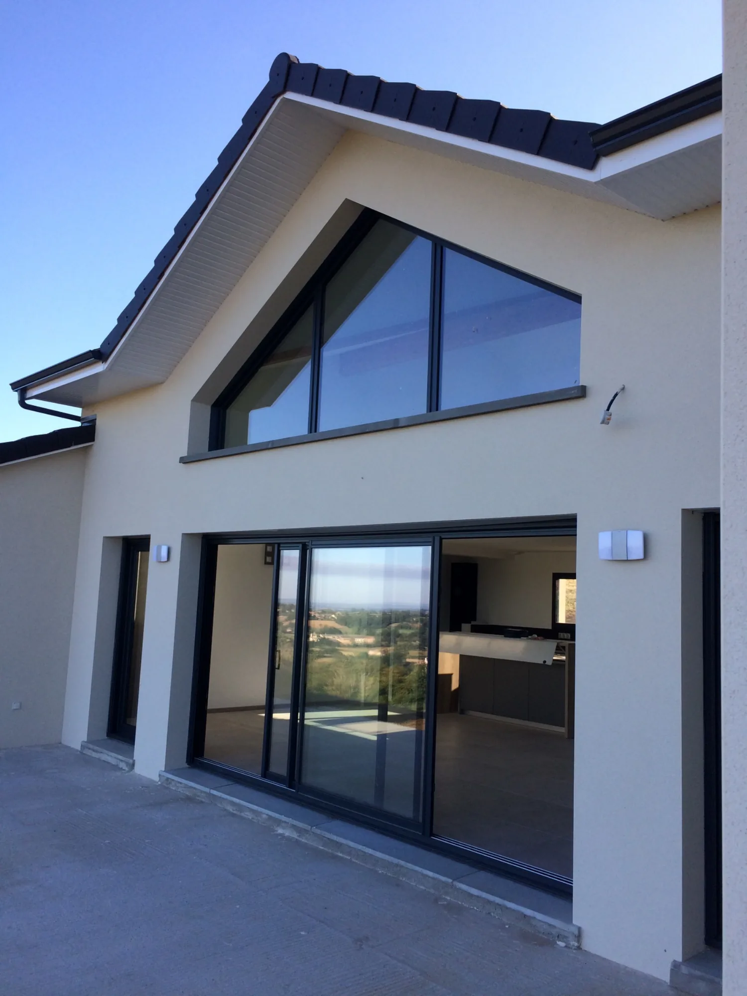 Maison neuve à pignon entièrement vitré, enduit blanc et toiture grise